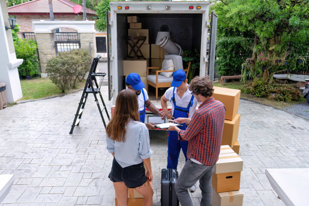 Two movers passing over a clipboard and a pen to a couple